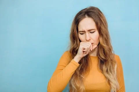 The girl coughs, covers her mouth. Portrait of a girl close-up with a cold. c Stock Photos