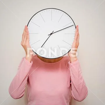 Girl covering her face from a clock. Woman hides from stress and deadline con Stock Photos