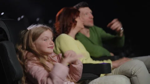 Girl Covers Her Ears While Parents Argue About Movie Plot in Cinema Video stock 298026092