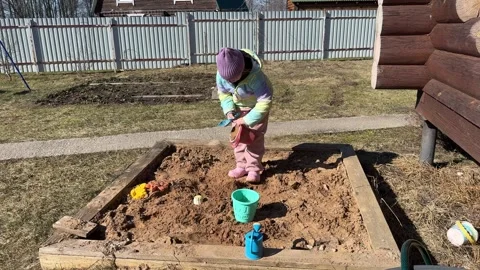 The girl creates different textured areas in the sandbox Stock Footage 320619087