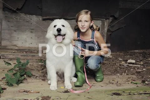 Girl crouching with dog in dilapidated shed Stock Photos