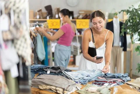 Girl customer scan QR code on trousers label. Female client looking for Stock Photos