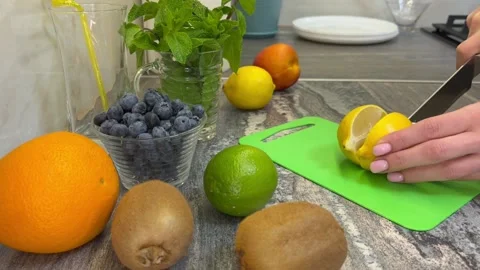 The girl cuts a lemon in the kitchen to make lemonade. Video stock 201168580