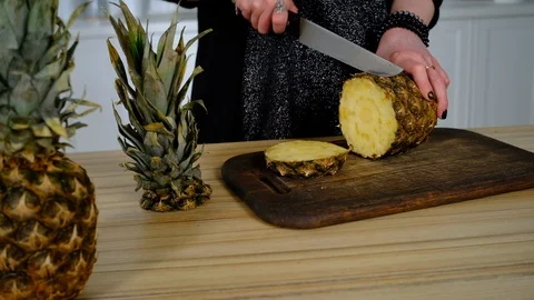 Girl cuts pineapple in the kitchen 库存影片 127290221