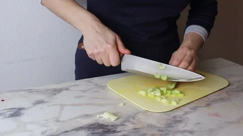 The girl cuts a stalk of celery with a large knife. Cooking vegetable salad Stock-Footage 308104103