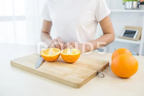 Girl cutting orange with the knife Stock-Fotos