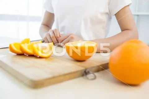 Girl cutting orange with the knife Stock-Fotos