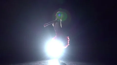 Girl dancing cha-cha-cha on a dark background with light illuminator. Slow Stock Footage 69798075