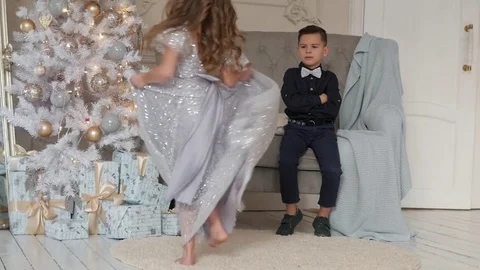 The girl is dancing in front of the boy in a beautiful dress. Christmas interior Vidéo 85154984