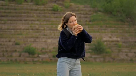 Girl dancing with a hot dog and eating it at the playground Stock Footage