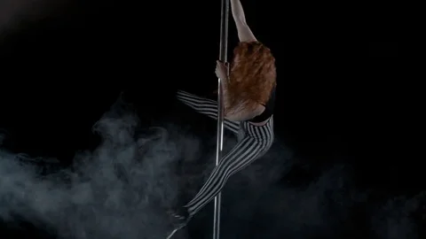 The girl is dancing Pole Dance on dark backgroun, in studio with smoke Stock Footage 76501737