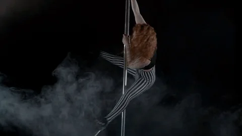 The girl is dancing Pole Dance on dark backgroun, in studio with smoke Stock Footage 76503934