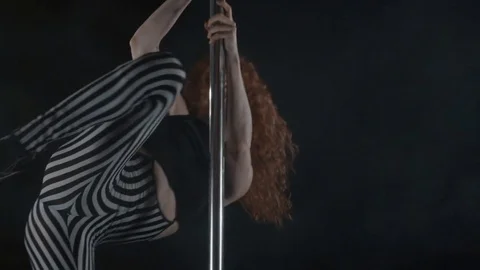 The girl is dancing Pole Dance on dark backgroun, in studio with smoke Stock Footage 76504011