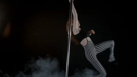 The girl is dancing Pole Dance on dark backgroun, in studio with smoke Stock Footage 76504097