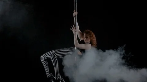 The girl is dancing Pole Dance on dark backgroun, in studio with smoke Stock Footage 76504256
