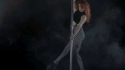 The girl is dancing Pole Dance on dark backgroun, in studio with smoke Stock Footage 76504320