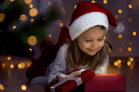 Girl at dark opens box with magic light next to christmas tree. New Year gift Stock Photos