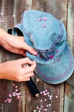 Girl decorating cap with sequins using thread and needle Stock Photos