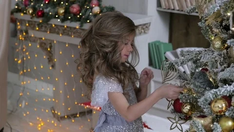 The girl is decorating a Christmas tree in a flattering dress with a train 動画素材 85151075