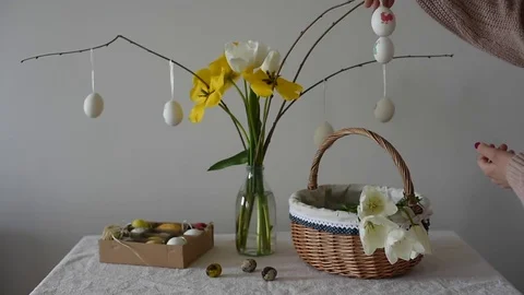 Girl decorating easter tree with eggs and tulips on a table with basket ful.. Stock Footage 74297825
