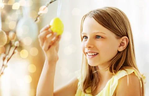 Girl decorating willow by easter eggs at home Stock Photos