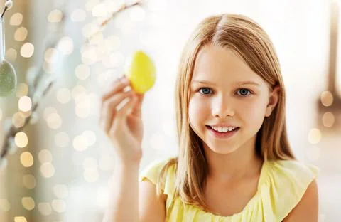 Girl decorating willow by easter eggs at home Stock Photos