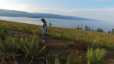 The girl descends down the path to the water. Green hills of Ogoi Island, Lake Video stock 128409450