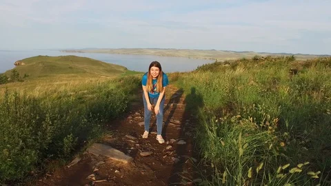 The girl descends down the path to the water. Green hills of Ogoi Island, Lake Stock Footage 128409997