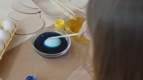 Girl Dipping Easter Egg in Blue Food Coloring Stock Footage 124576739