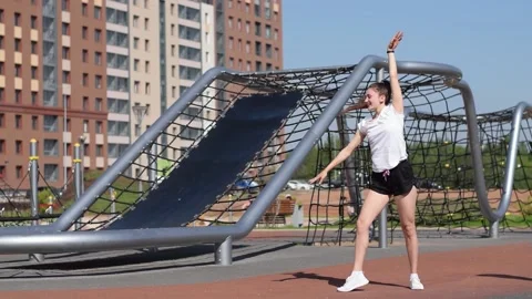 Girl does acrobatic stunt wheel and swings her leg on the playground. Stock Footage 154846396