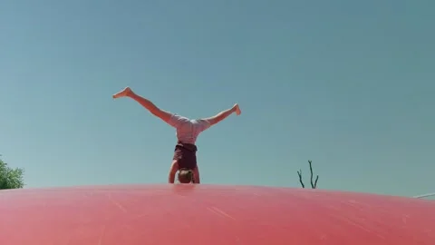 A Girl does a Handstand on a Trampoline Stock-Footage 345877728