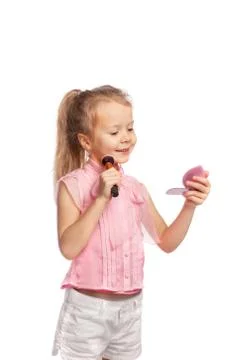 Girl does makeup using lip gloss, looking in a small hand mirror Stock Photos