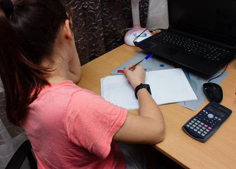 Girl Does math Homework in Her Living Room. She's Sitting at Her Desk Writes Stock Photos