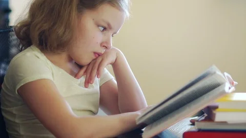 The girl does not want to learn lessons, she's bored, she pushes a pile of books Stock Footage 89485871