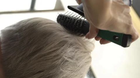 Girl does styling with a comb and dries hair with a hairdryer to the client Stock Footage 124705292