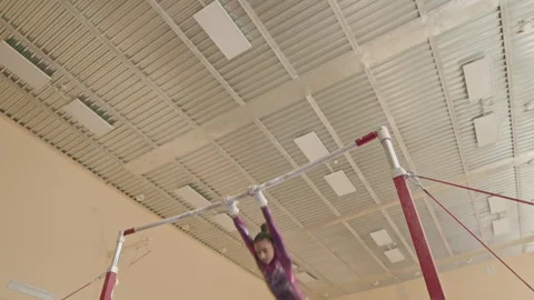 Girl Doing Artistic Elements on Uneven Bars Indoors Stock Footage 252270702