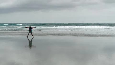Girl doing exercises on an empty beach, New Zealand. Stock Photos