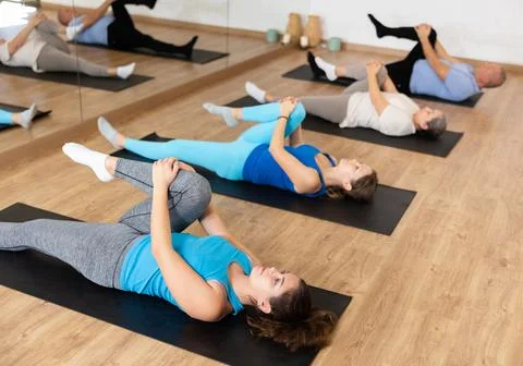 Girl doing hamstrings stretching exercises during group training Stock Photos