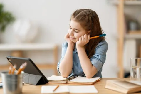 Girl doing homework or online education. Stock Photos