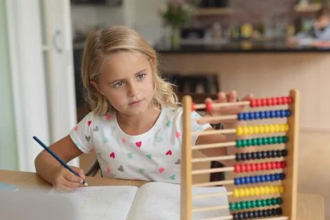 Girl doing homework at table in a comfortable home 스톡 사진
