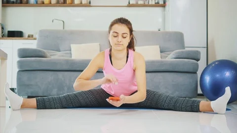 The girl is doing homework while doing exercises from the phone. Stock Footage 102082444