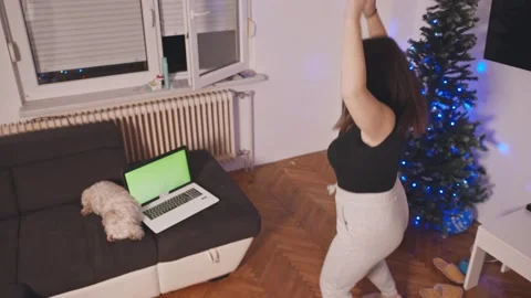 A girl doing a jumping jack and watching online tutorials on laptop Stock Footage 145664532