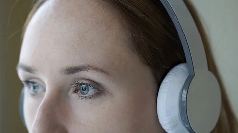 Girl doing pensive look to the camera while listening music on headphones, stead Vídeos de archivo 75605801