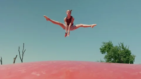 A Girl is doing the Splits on a Trampoline Video stock 345710297