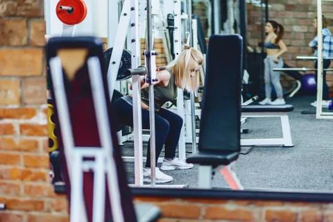 Girl is doing squats in simulator Stock Photos