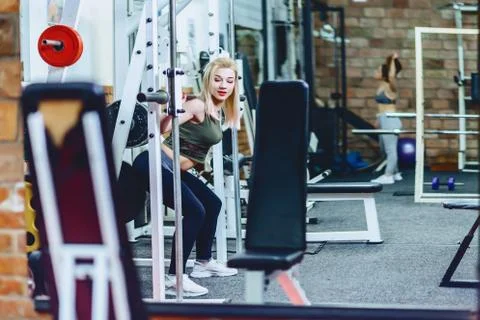 Girl is doing squats in simulator Stock Photos
