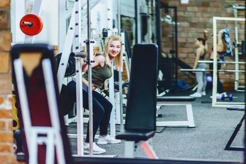 Girl is doing squats in simulator Stock Photos