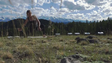 Girl doing yoga on the grass on the background of snow-capped mountains 4K Stock Footage 124425552