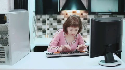Girl with Down syndrome sitting at a computer at home and typing text. . March Video stock 72199247