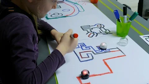 Girl is drawing path for mini robot. Mini robot follows the line Stock Footage